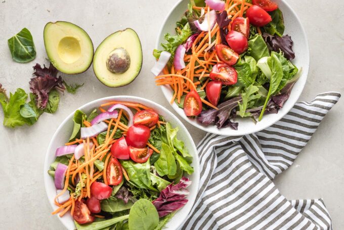Lettuce, onion, carrots, and tomato in two small bowls.