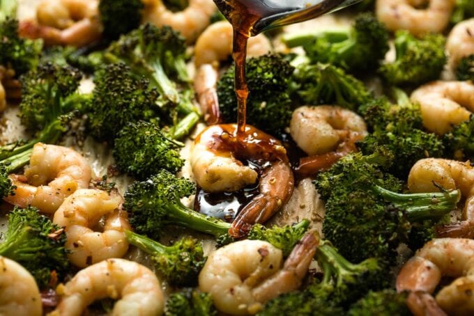 Honey garlic sauce being poured onto cooked shrimp.