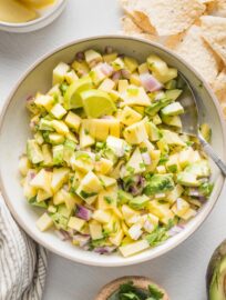 Bowl filled with mango avocado salsa and tortilla chips off to the side.