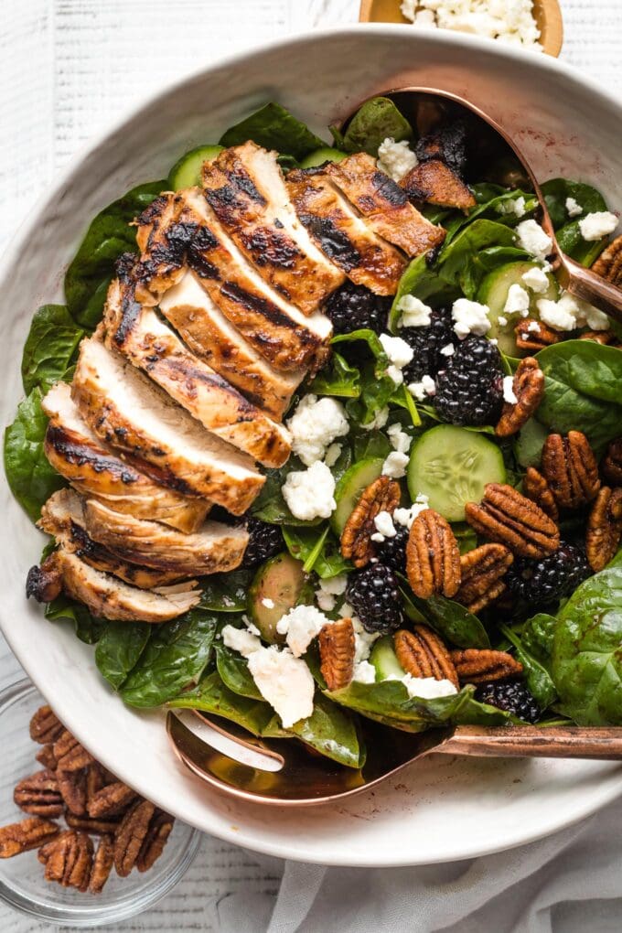 Close-up of spinach blackberry salad in a white serving bowl.