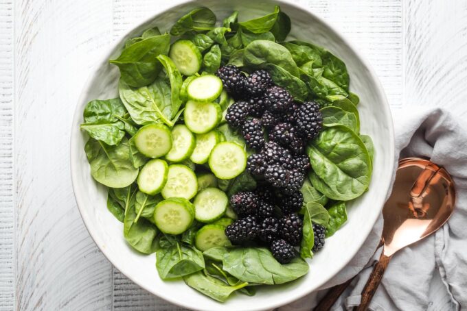 Spinach, blackberries, and cucumber in a bowl.