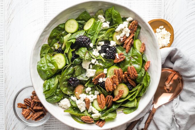 Veggies and fruit tossed in dressing with feta and pecans sprinkled on top.