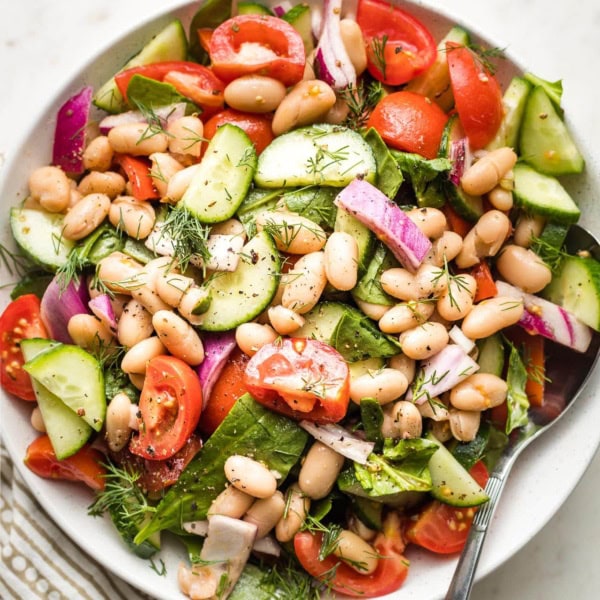 Close-up of white bean salad in a small white serving bowl.