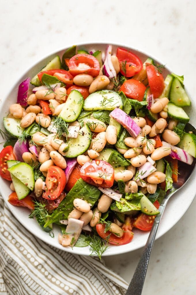 Close-up of white bean salad in a small white serving bowl.