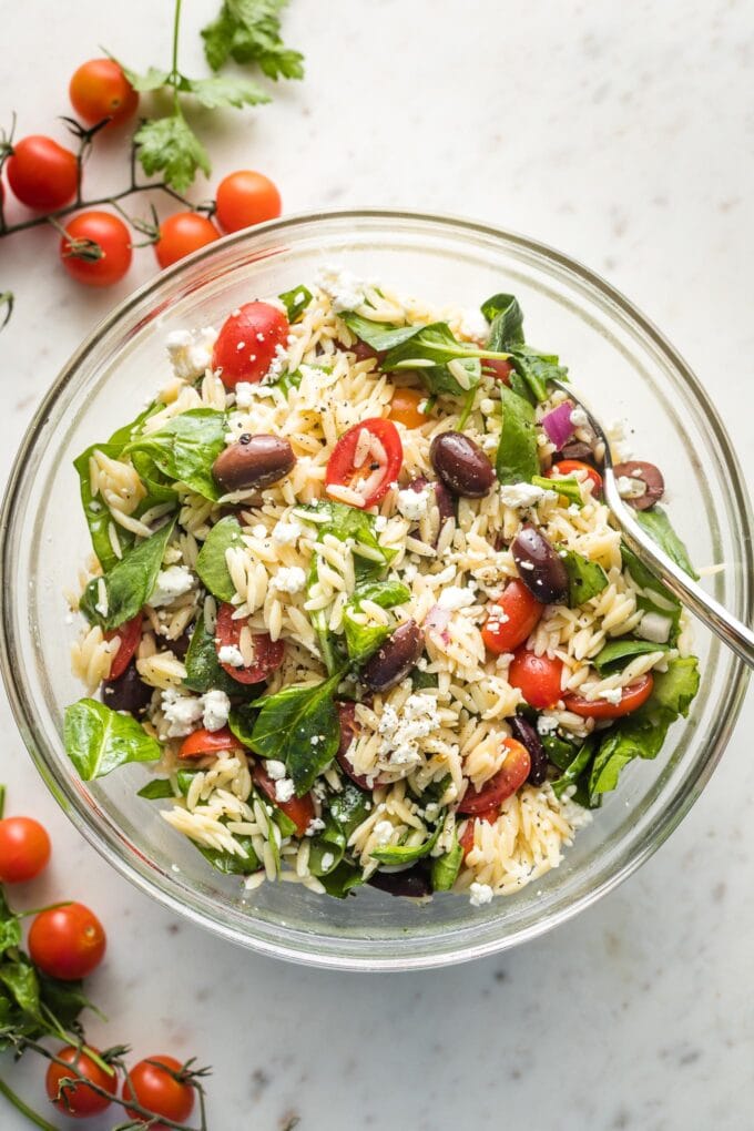 Clear bowl containing a Mediterranean orzo salad, ready to serve.