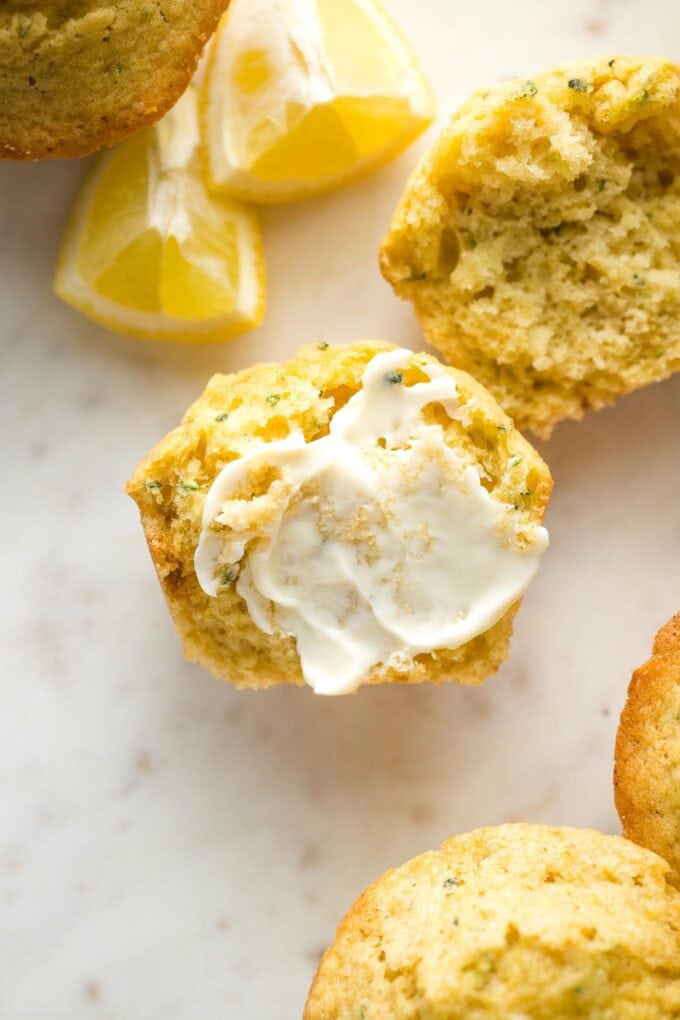 Close-up of a lemon zucchini muffin split open and served with soft butter.