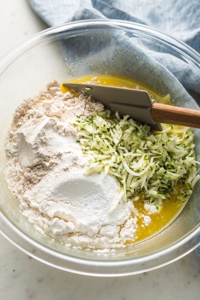 Prep bowl with egg mixture, flour, and grated zucchini.