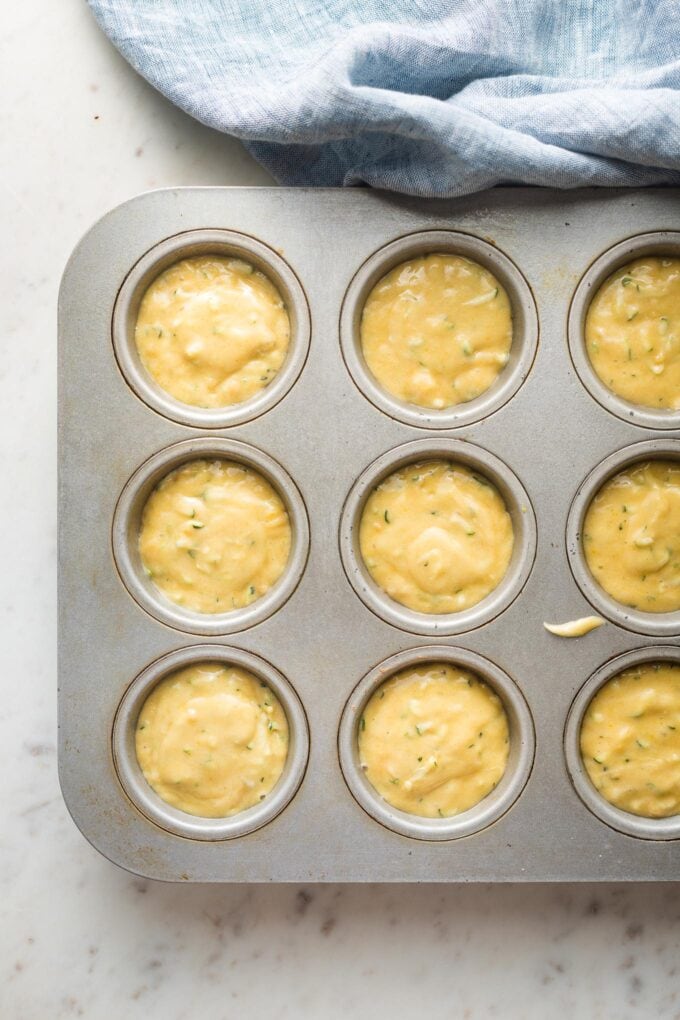 Muffin batter divided among wells of a baking pan.