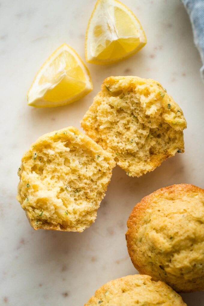 Close up of a lemon zucchini muffin split open to reveal the moist crumb and tender texture.