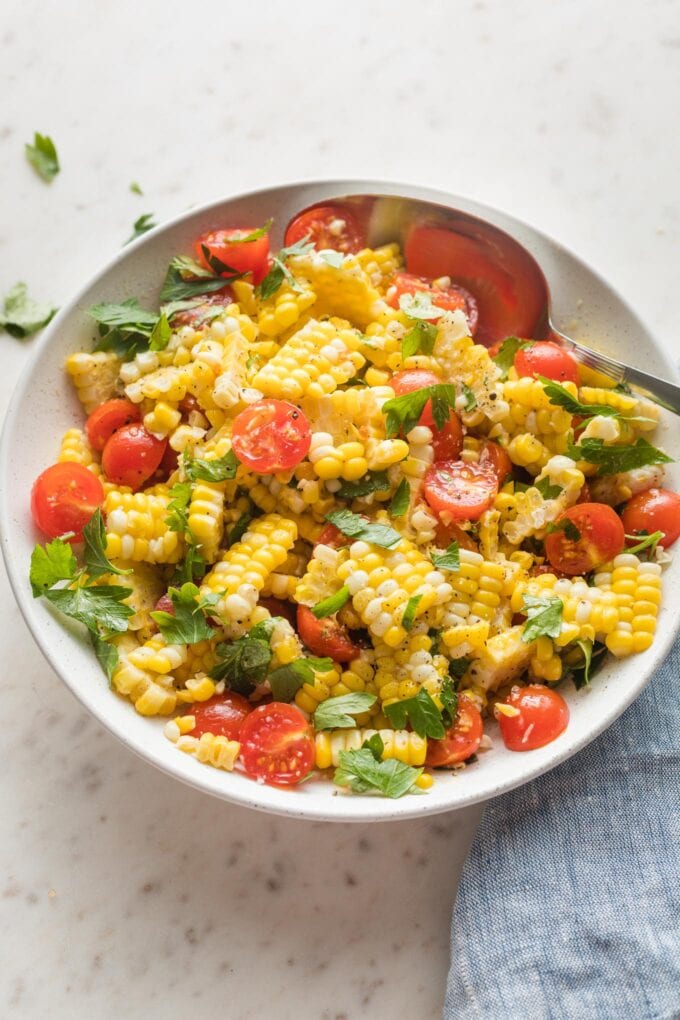 Roasted corn and tomato salad in a white bowl.