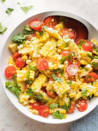 Roasted corn and tomato salad in a white bowl.