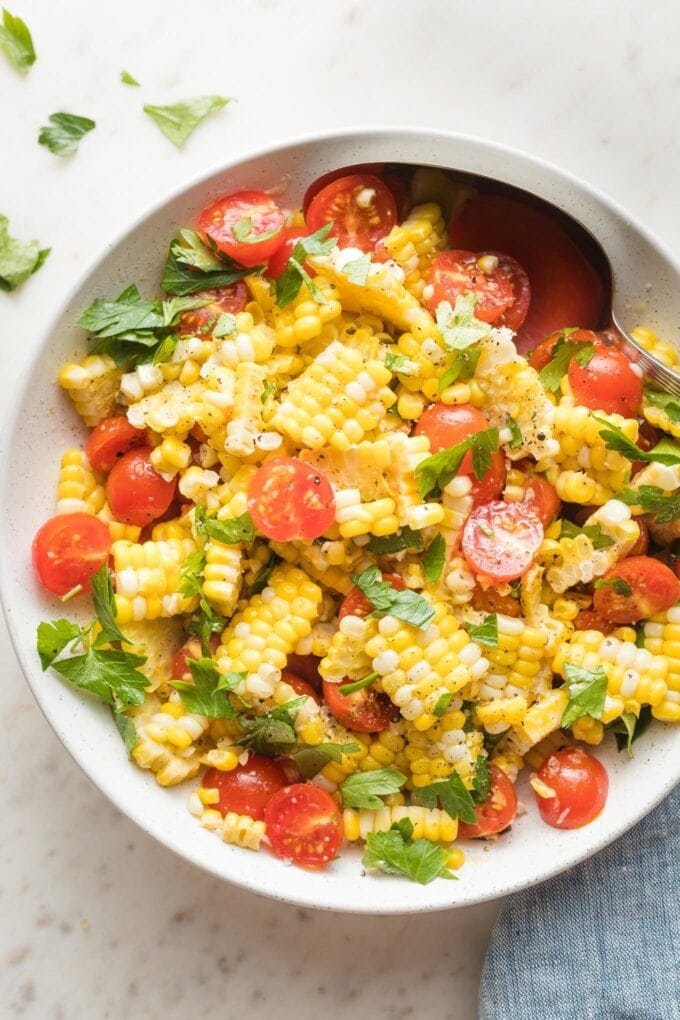 Roasted corn and tomato salad in a white bowl.