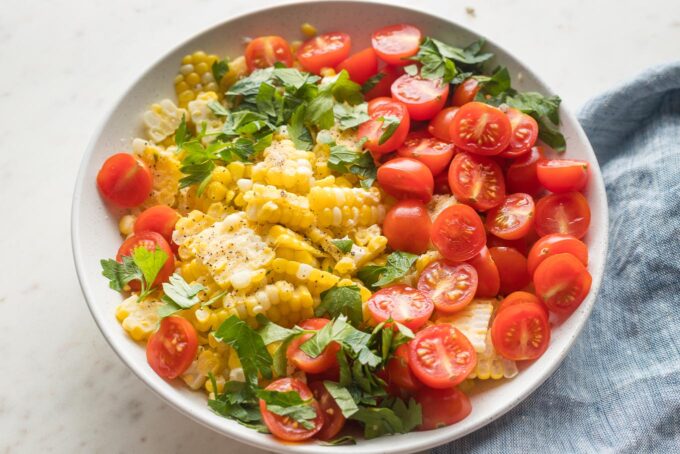 Small bowl with corn, cherry tomatoes, and fresh chopped parsley.