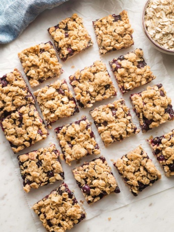 Squares of blueberry oatmeal bars arranged on parchment paper.