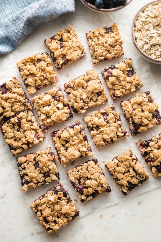 Squares of blueberry oatmeal bars arranged on parchment paper.