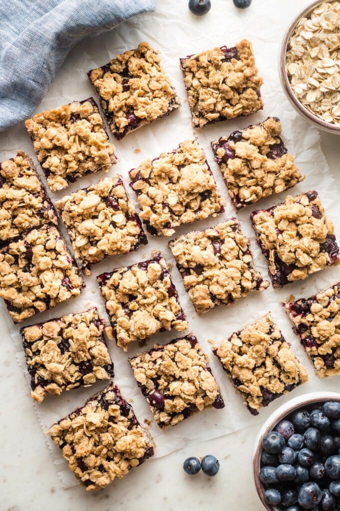 Squares of blueberry oatmeal bars arranged on parchment paper.