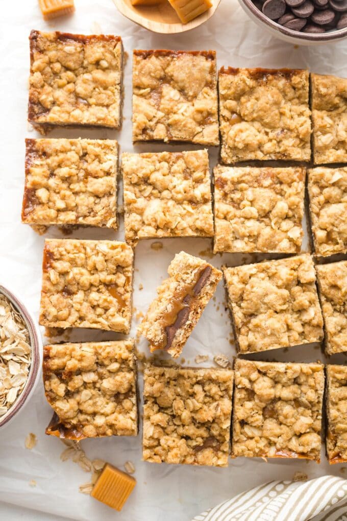 Just-cut squares of carmelita bars, laid out on white parchment paper.
