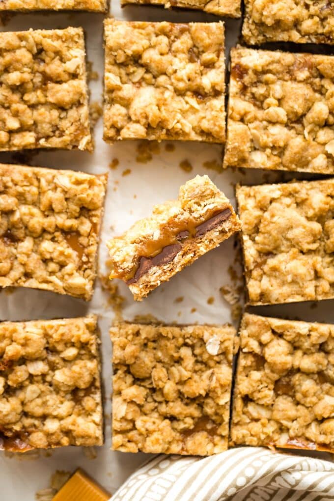 Close up of carmelita bars, with one turned on its side to show layers of gooey caramel and chocolate.
