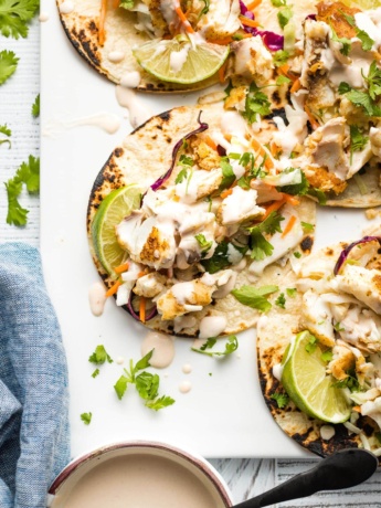 Fish tacos with slaw and crema arranged on a platter.