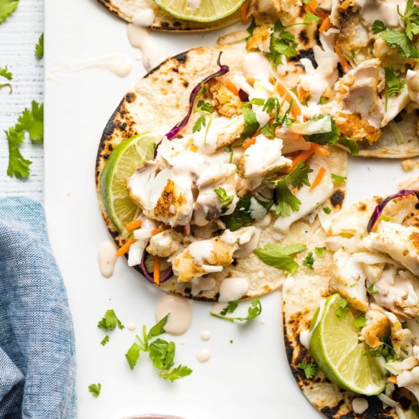 Fish tacos with slaw and crema arranged on a platter.