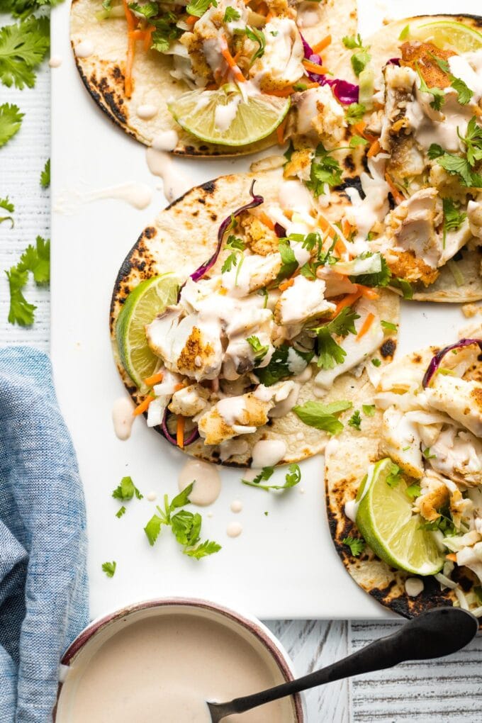 Fish tacos with slaw and crema arranged on a platter.