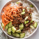 Close up of Korean ground beef served over rice and with an array of fresh veggies.