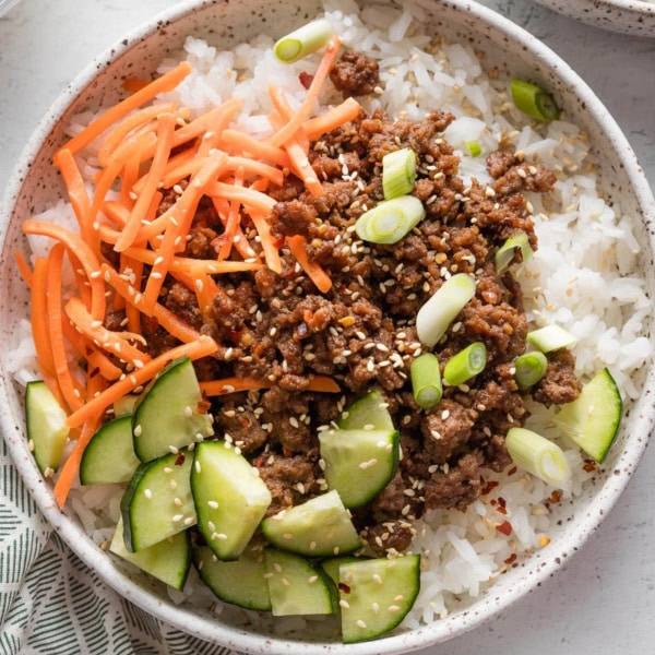 Close up of Korean ground beef served over rice and with an array of fresh veggies.