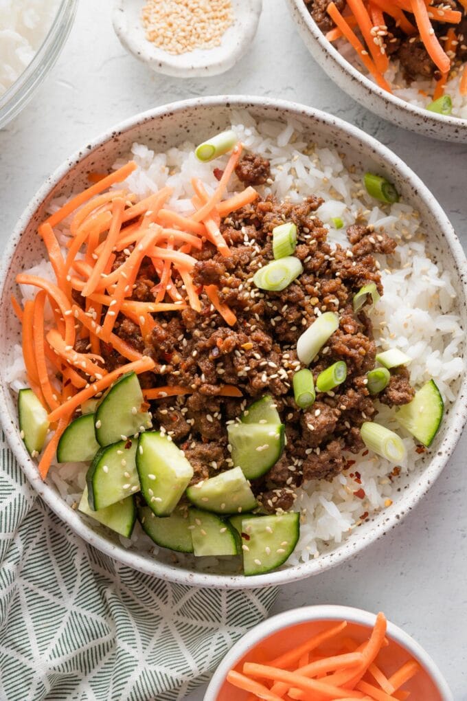 Close up of Korean ground beef served over rice and with an array of fresh veggies.