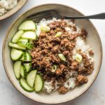 Small bowl filled with Korean ground beef, rice, and sliced cucumbers.