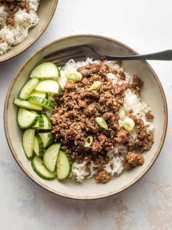 Small bowl filled with Korean ground beef, rice, and sliced cucumbers.