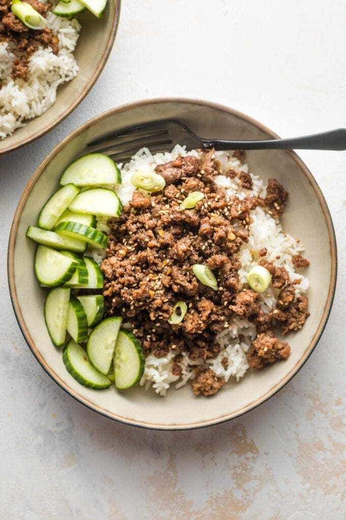 Small bowl filled with Korean ground beef, rice, and sliced cucumbers.