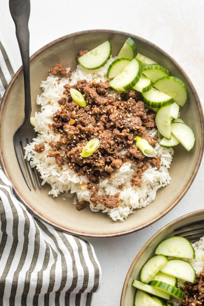 Small bowl filled with Korean ground beef, rice, and sliced cucumbers.