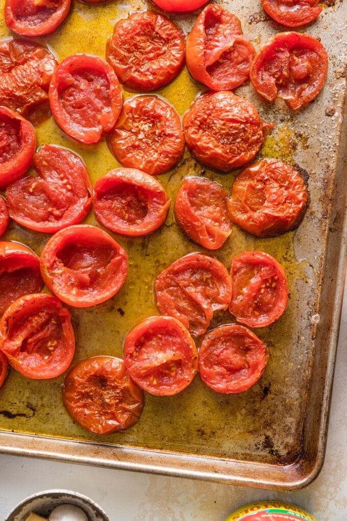 Roasted tomatoes shriveled and browned on a rimmed baking sheet.