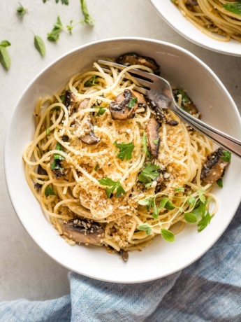 Bowl of garlic mushroom spaghetti with fresh oregano and toasted garlicky breadcrumbs.