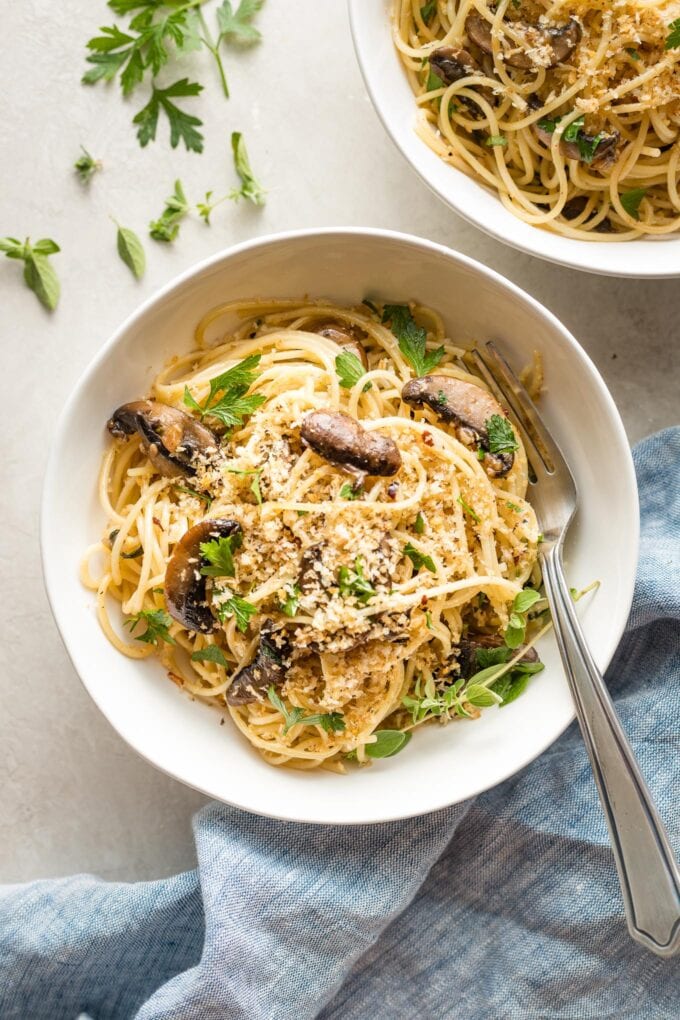 Bowl of spaghetti with mushrooms, oregano, and toasted breadcrumbs.