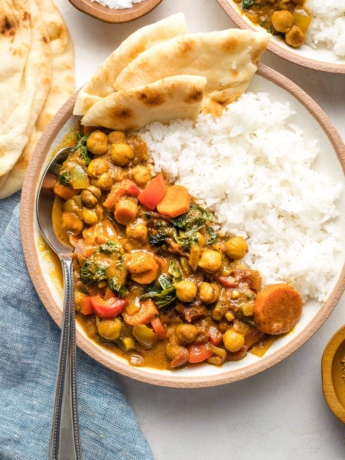 Bowl of Instant Pot chickpea curry served with rice and naan.