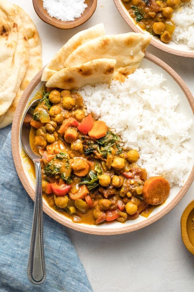 Bowl of Instant Pot chickpea curry served with rice and naan.