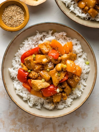 Bowls of pineapple chicken served with rice.