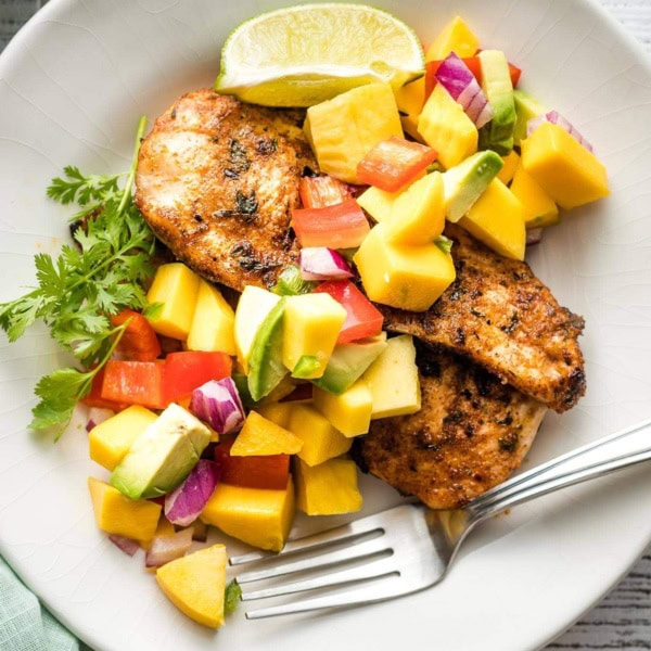Grilled jerk chicken with mango avocado salsa served on a plate.