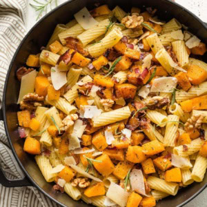 Roasted butternut squash pasta with rosemary and bacon in a skillet.
