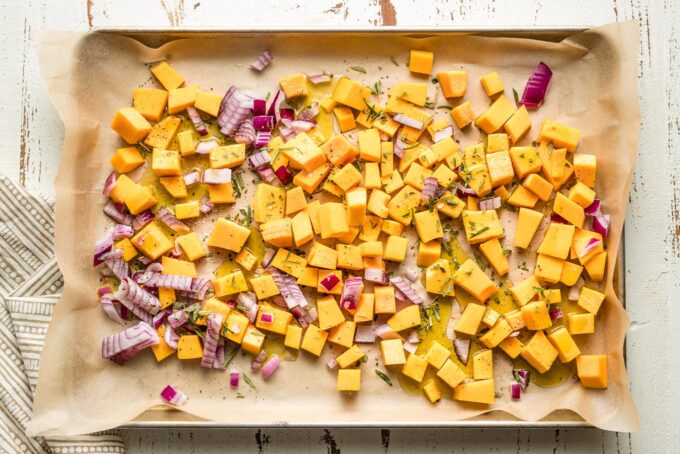 Baking sheet with squash, onion, and seasonings.