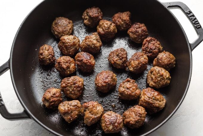Cooked lamb meatballs in a skillet.