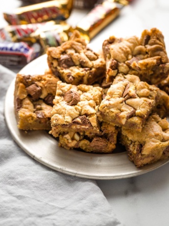 Blondies with candy bars mixed in, arranged on a small plate.