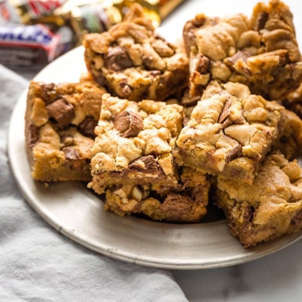 Blondies with candy bars mixed in, arranged on a small plate.