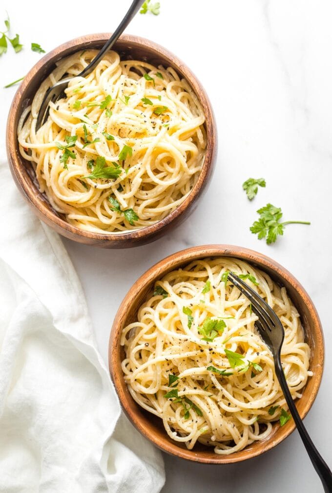 Two small wooden bowls with creamy garlic butter pasta ready to eat.