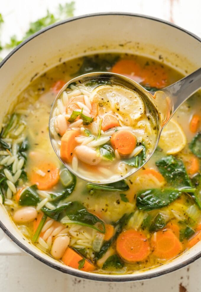 Large pot of white bean and spinach soup with orzo and lemon.