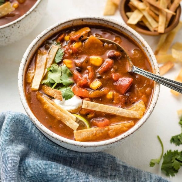 Bowl of chipotle black bean tortilla soup garnished with tortilla strips and cilantro.