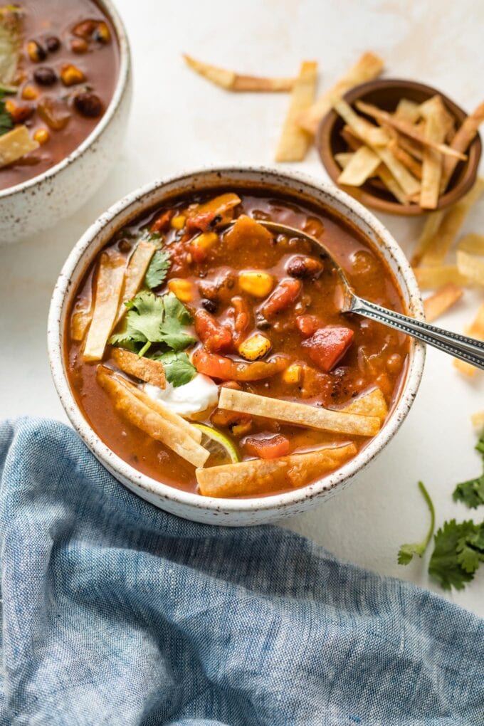 Bowl of chipotle black bean tortilla soup garnished with tortilla strips and cilantro.