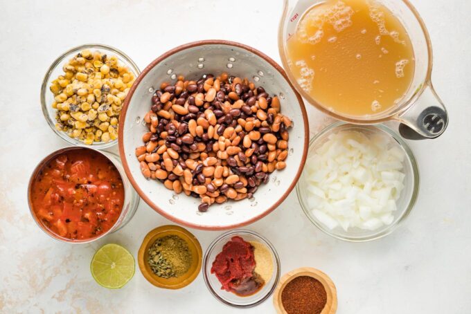Beans, tomatoes, broth, corn, onions, and spices arranged in prep bowls.