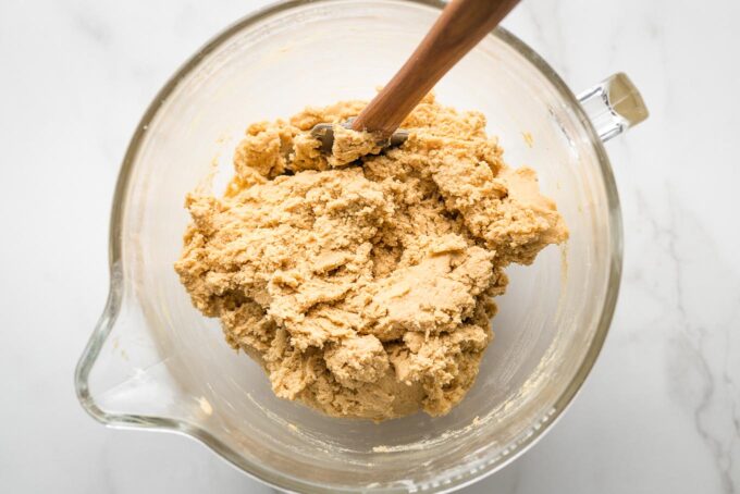Clear mixing bowl full of peanut butter cookie dough.